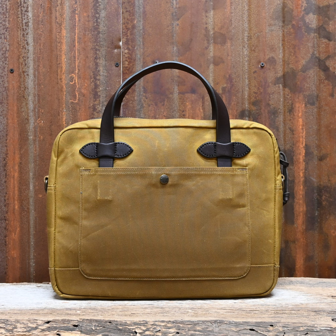 View of Filson Tin Cloth Compact Briefcase in Dark Tan, showcasing its durable waxed cotton exterior, leather handles, and padded laptop compartment