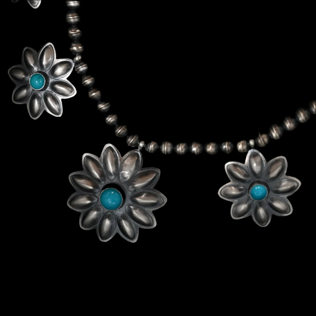 View of Robert Johnson Turquoise Stone Flower Necklace featuring nine sterling silver flowers with turquoise stones at the center