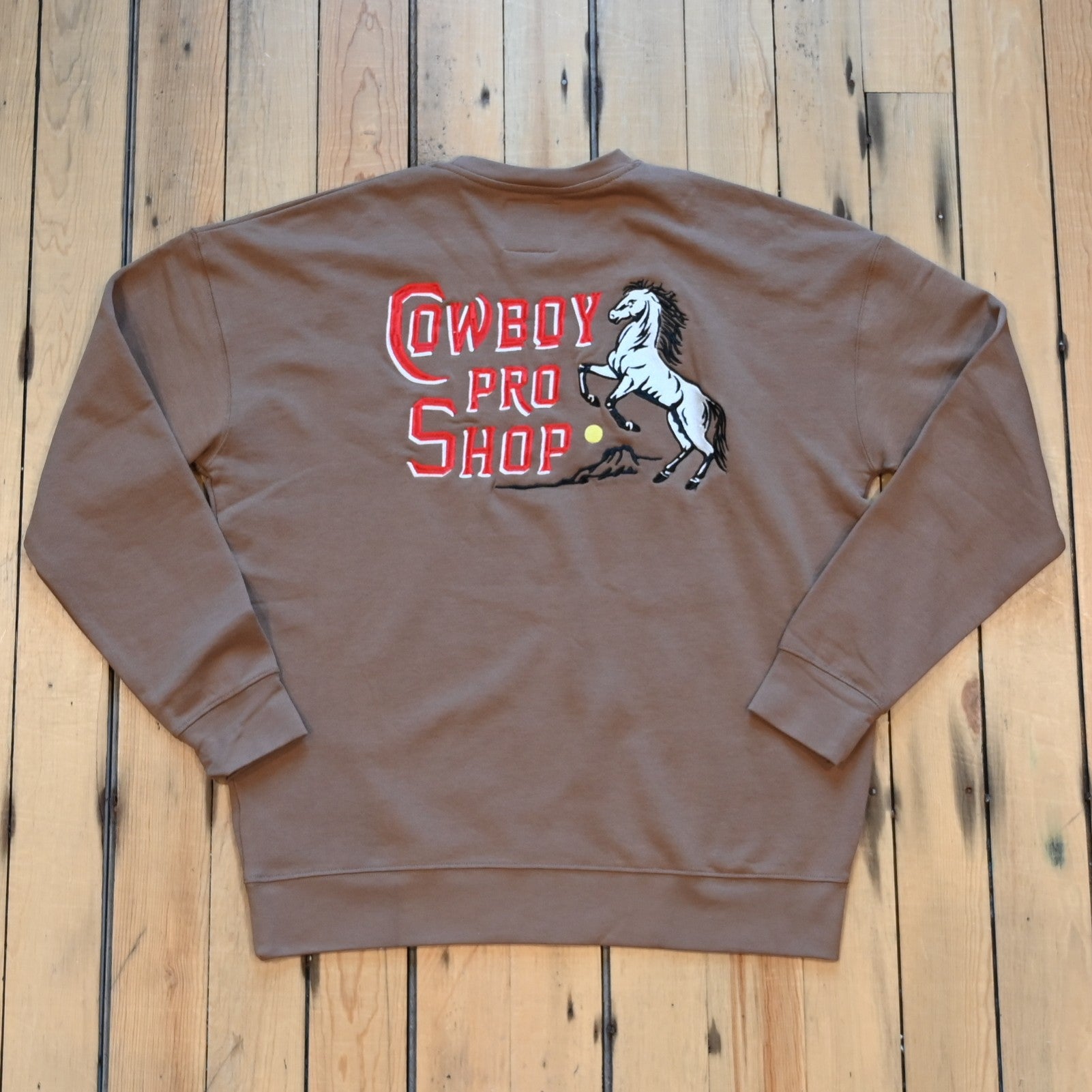 Crewneck sweatshirt with “Cowboy Pro Shop” and horse silhouette graphic in Western style