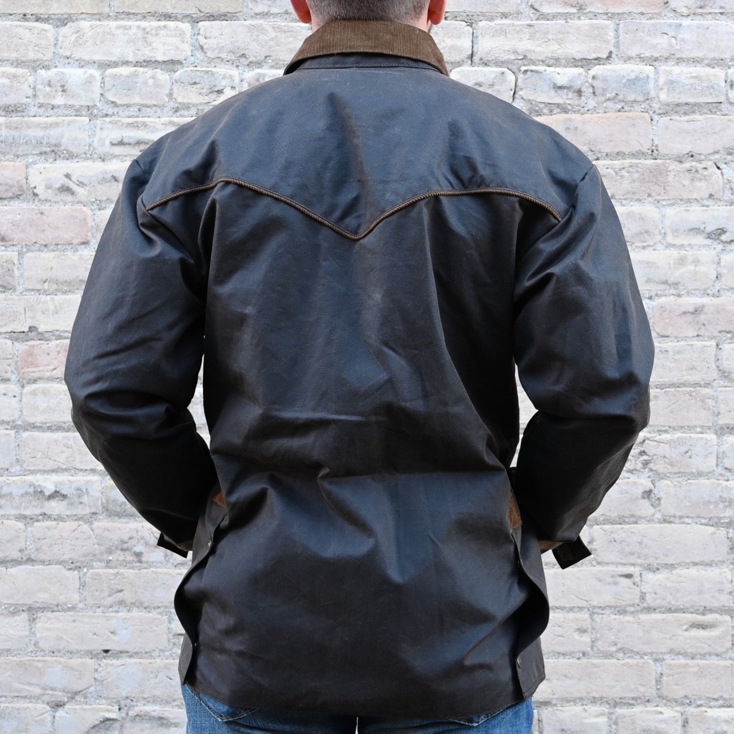 View of Oak waxed canvas RangeWax Drifter coat with leather collar, corduroy trim, pockets, and storm flap