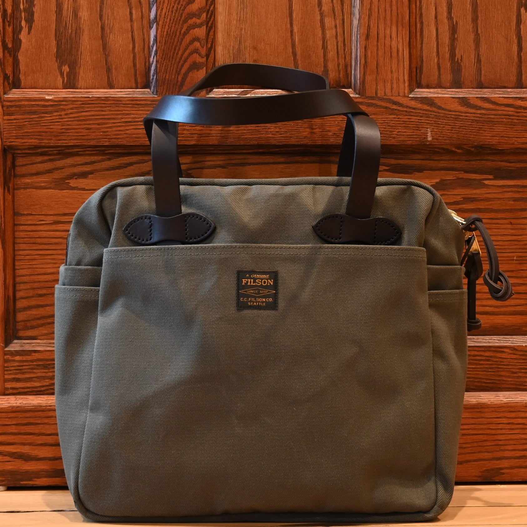Filson rugged twill zip-top tote bag in otter green with leather handles and multiple exterior pockets