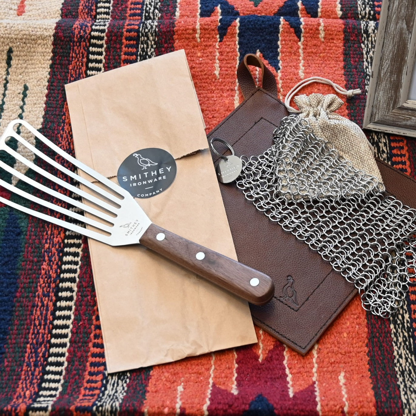 View of Smithey Ironware Universal Tool Bundle: slotted spatula, leather potholder, and chainmail scrubber