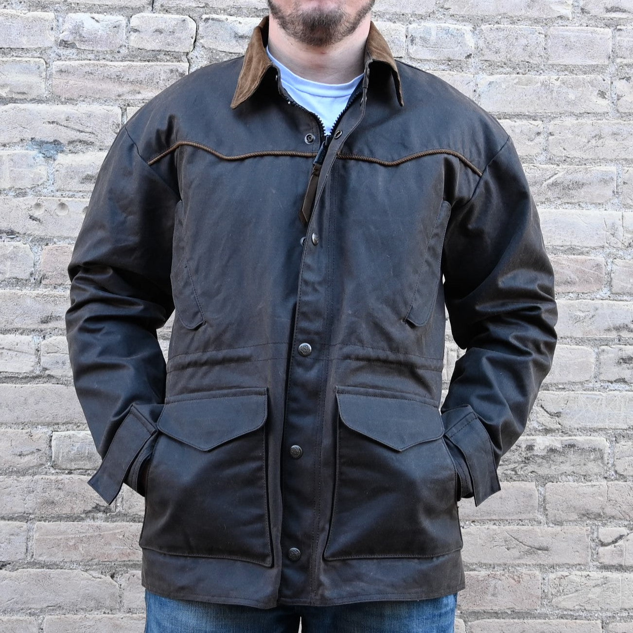 View of Oak waxed canvas RangeWax Drifter coat with leather collar, corduroy trim, pockets, and storm flap