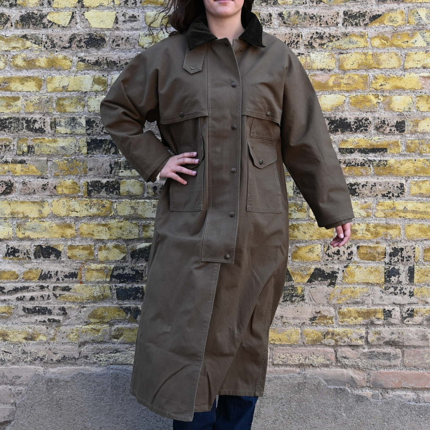 View of Filson Ladies Duster Coat in Marsh Olive featuring cape over shoulders, four front cargo pockets, and corduroy-lined collar