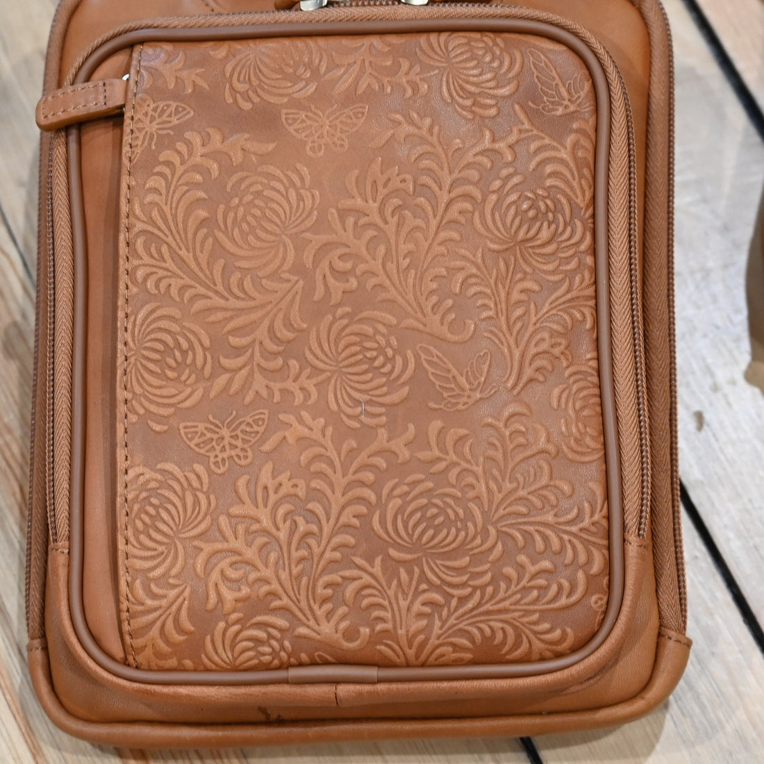 Tan leather crossbody shoulder pouch with embossed front, designed for concealed carry