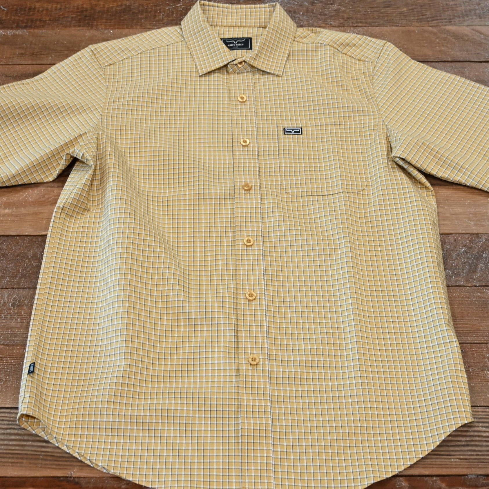 View of Kimes Ranch MC Cooper Short Sleeve Button-Up Shirt in Gold, featuring a grid plaid pattern and snap button front