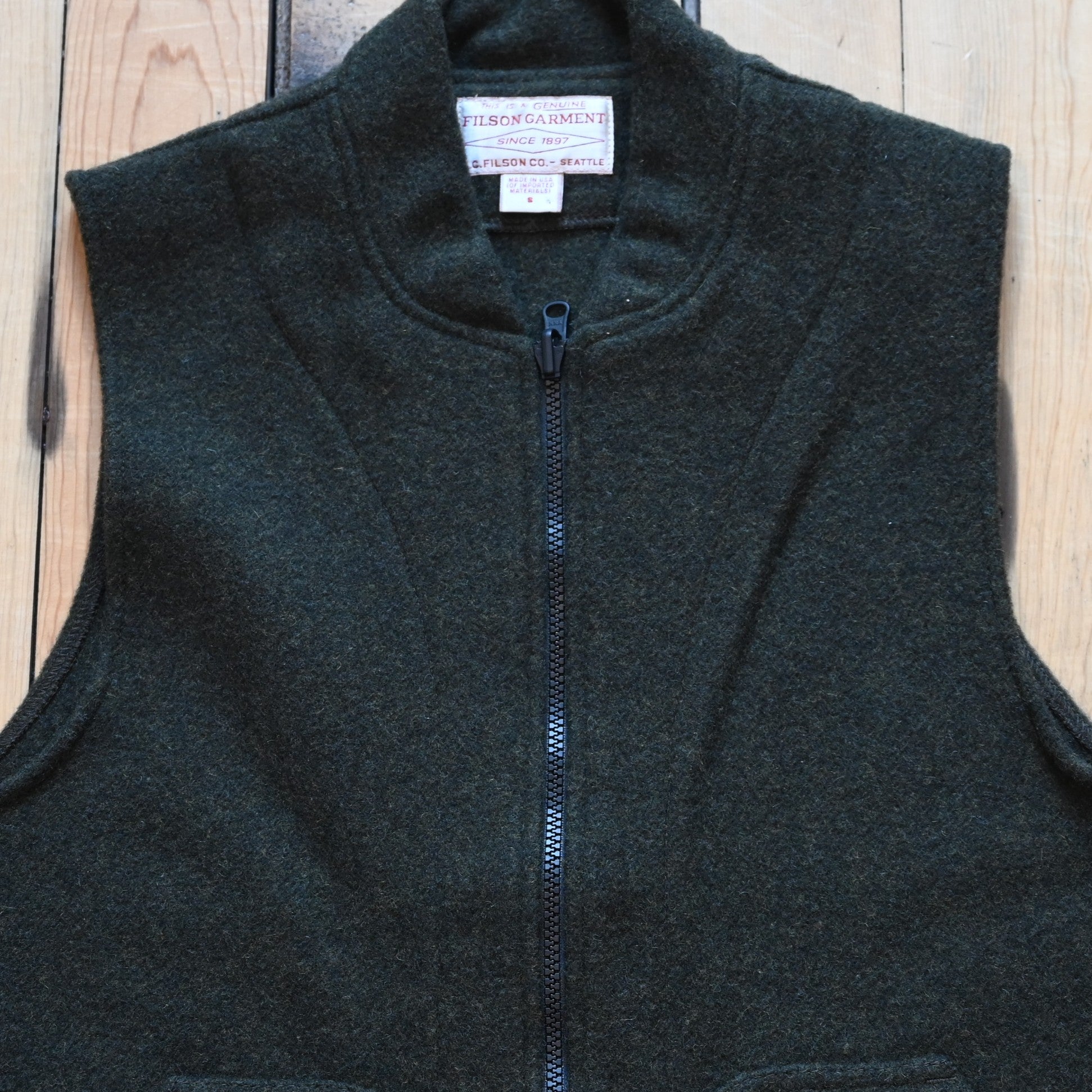 Forest green Filson Mackinaw Wool Vest Liner with zip-front, hand-warmer pockets, standing collar, and drawcord waist