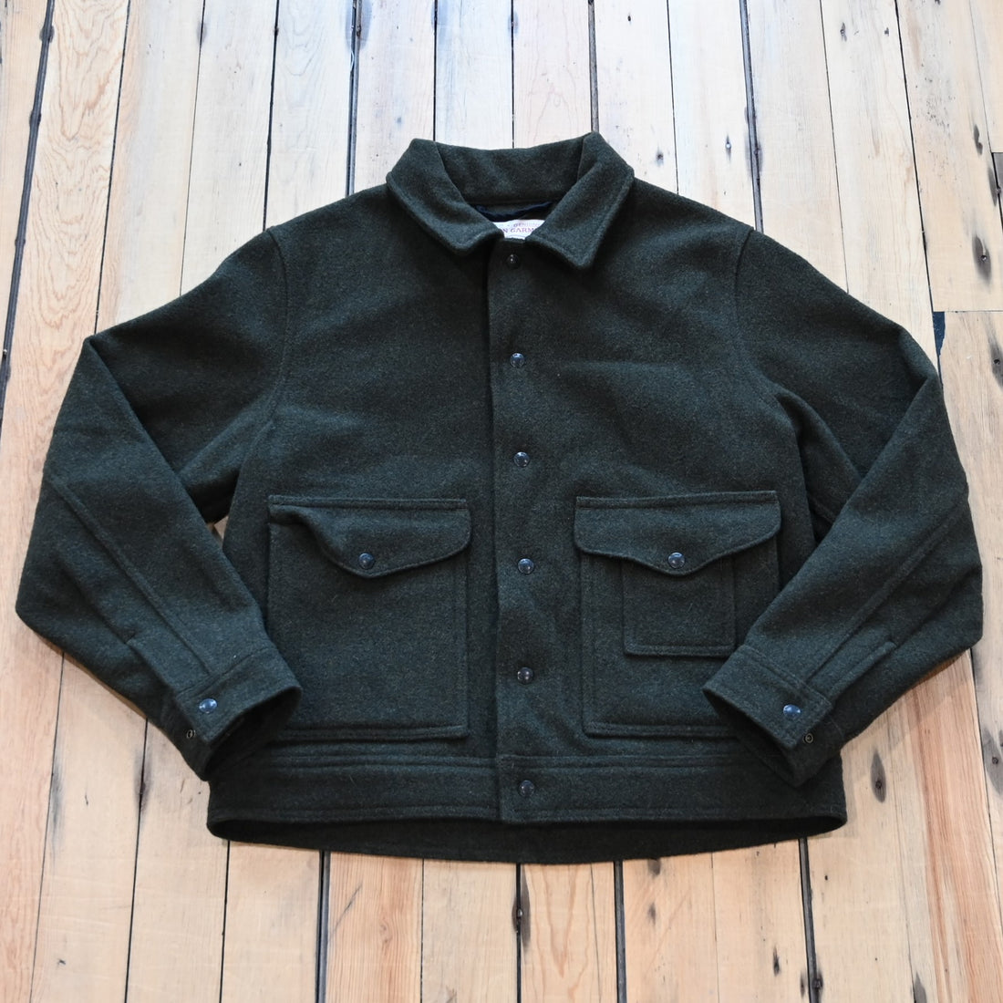 View of Filson Mackinaw Wool Work Jacket in Forest Green, showcasing snap-flap cargo and patch-hand pockets, and an internal stow pocket