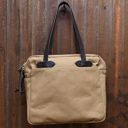 View of Filson Rugged Twill Tote Bag with Zipper in Tan, showcasing durable waxed cotton and leather handles