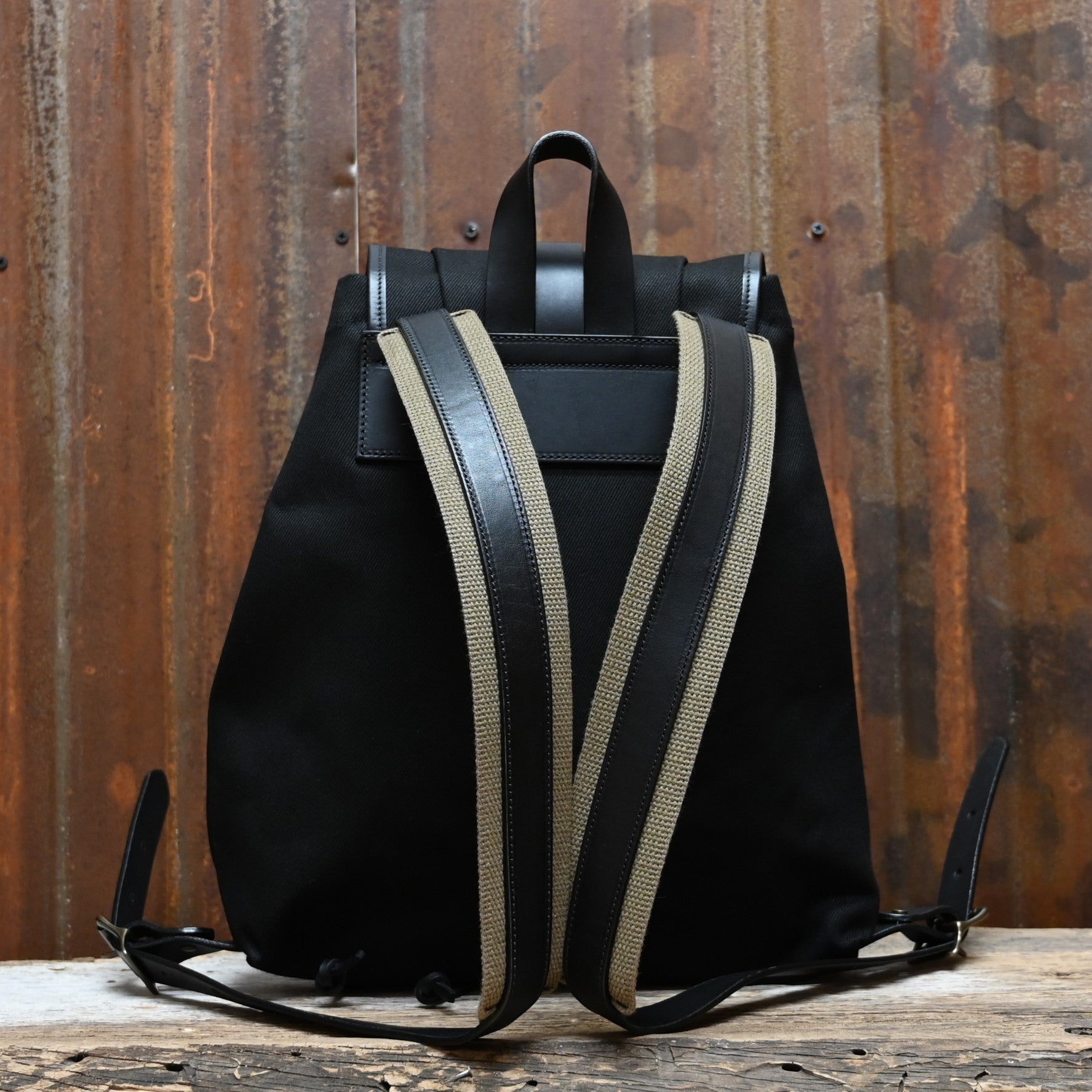 View of Filson Rugged Twill Drawstring Backpack in Black featuring leather straps and a rain flap