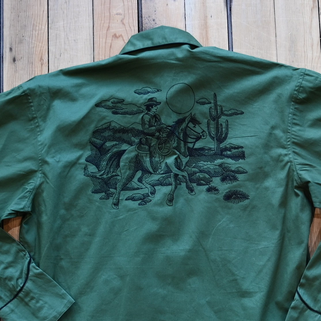 View of Green Western shirt with embroidered “man and rider” motif across yokes and cuffs