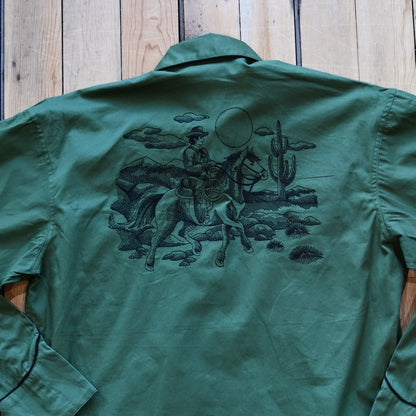 View of Green Western shirt with embroidered “man and rider” motif across yokes and cuffs