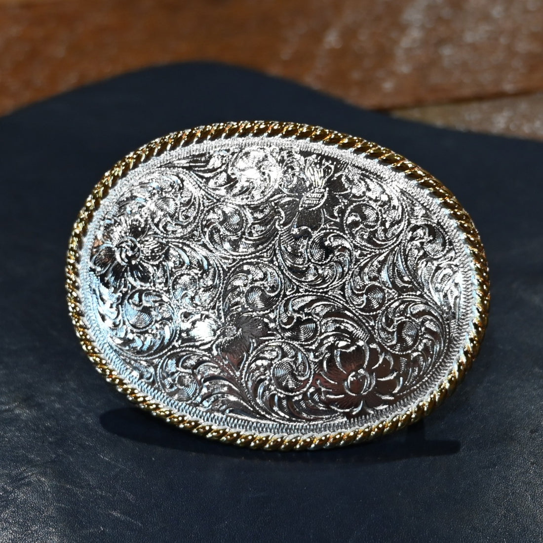 Nocona oval buckle with gold rope edge and engraved floral scroll design