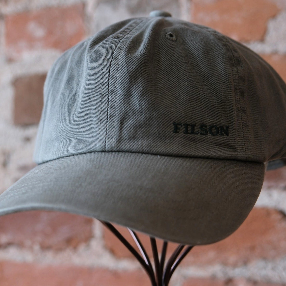 Filson Washed Low-Profile Logger Cap in Washed Olive featuring a 6-panel design and embroidered Filson logo.