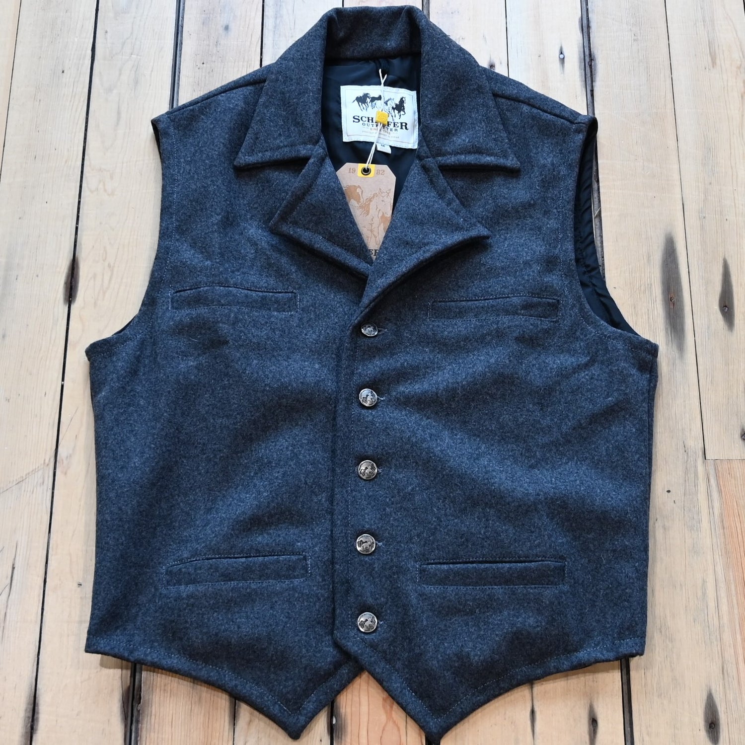 View of Charcoal Schaefer Cattle Baron wool vest with lapel collar, four pockets, and brass buttons