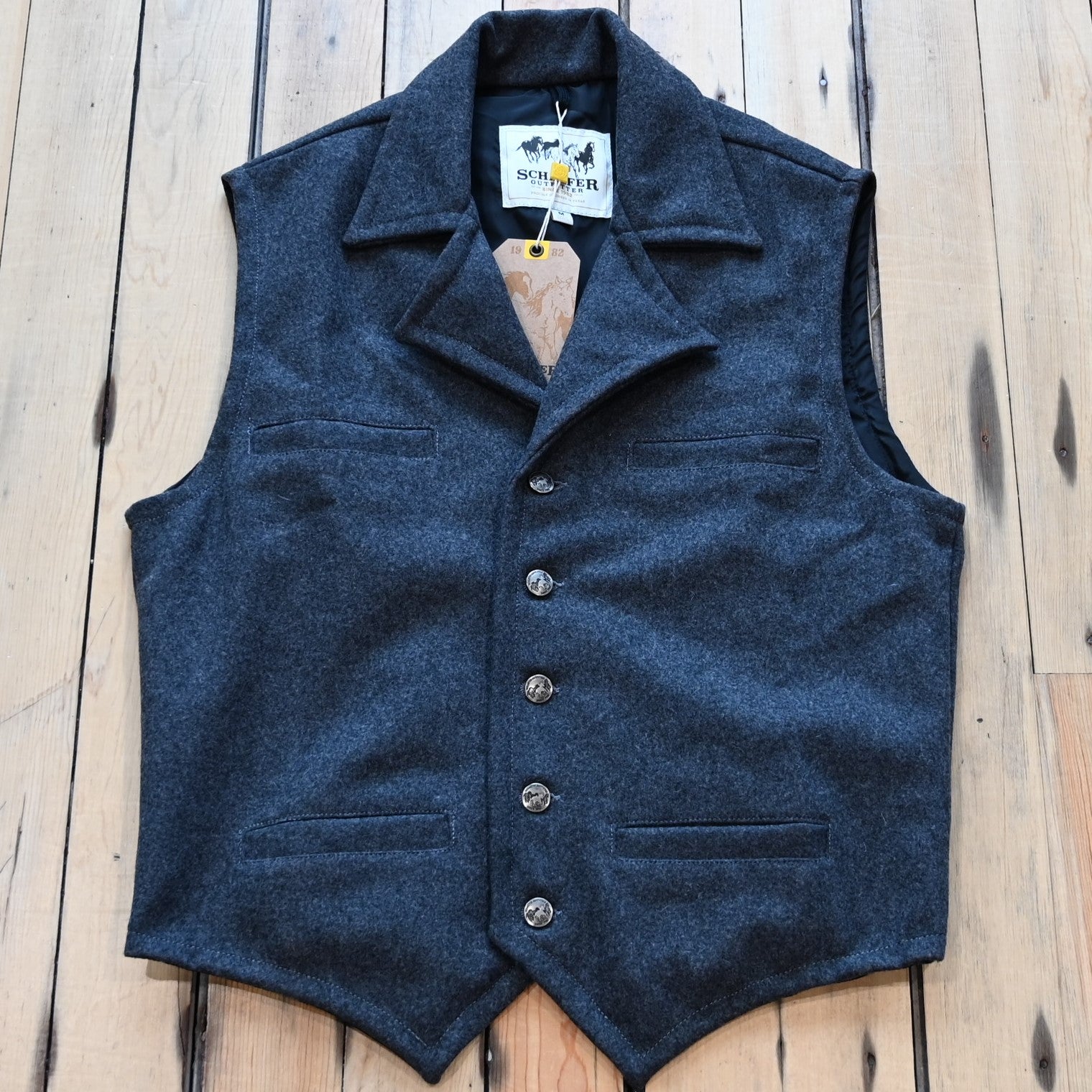 View of Charcoal Schaefer Cattle Baron wool vest with lapel collar, four pockets, and brass buttons
