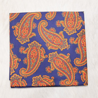 View of Schaefer paisley wild rag scarf in blue, orange and red with bold border and rolled edges
