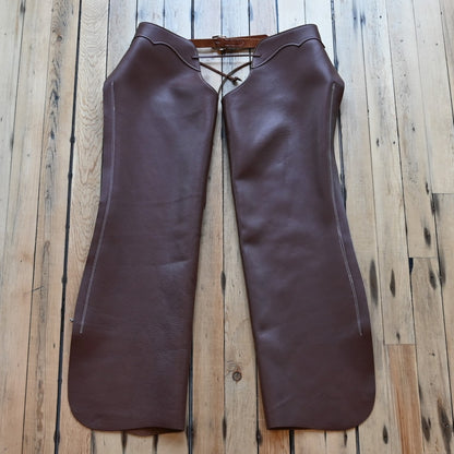 View of Weaver Shotgun Full Grain Chaps in brown oil-tanned leather with adjustable closures.