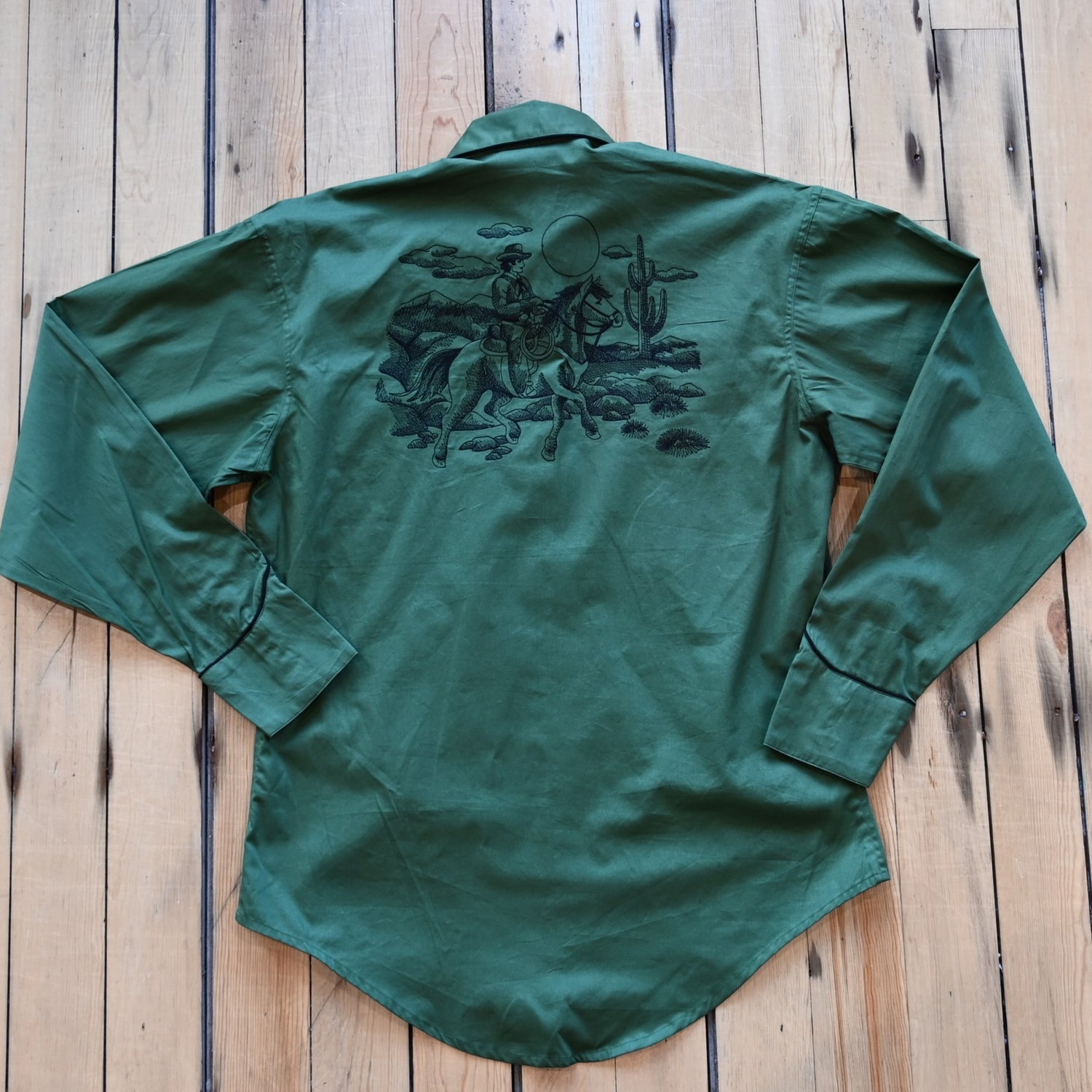 View of Green Western shirt with embroidered “man and rider” motif across yokes and cuffs