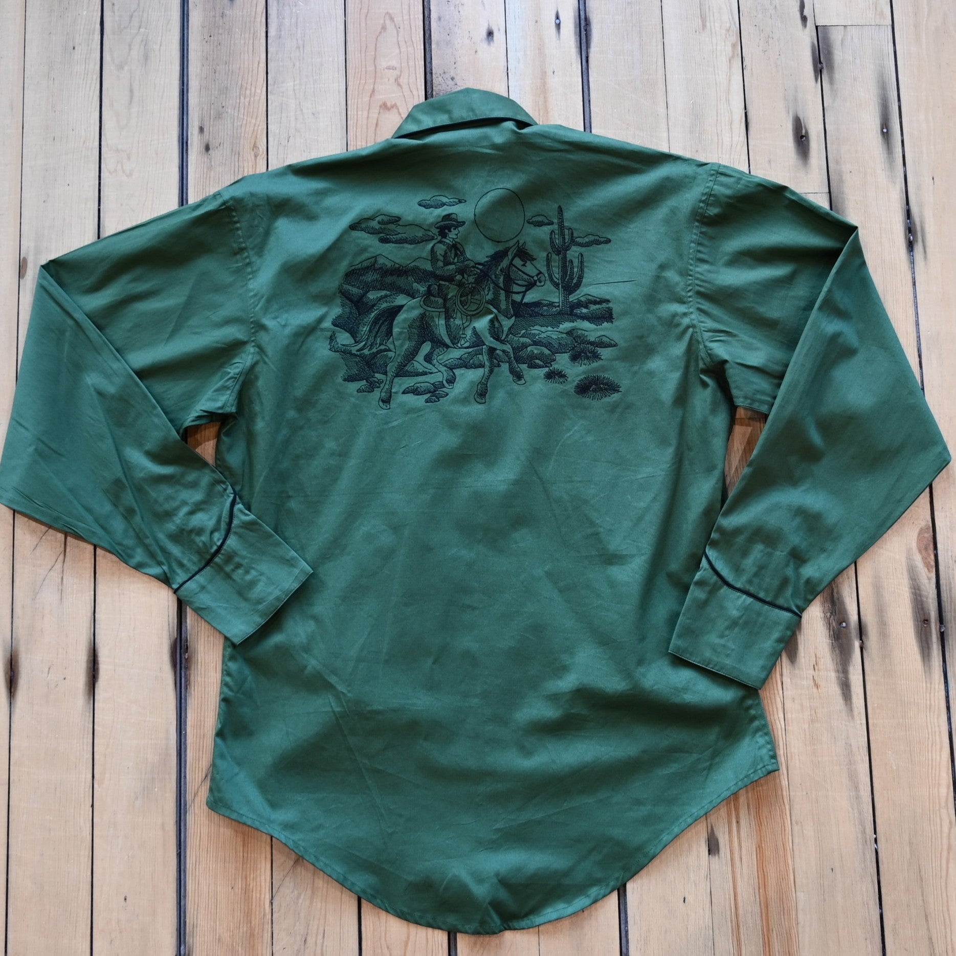 View of Green Western shirt with embroidered “man and rider” motif across yokes and cuffs