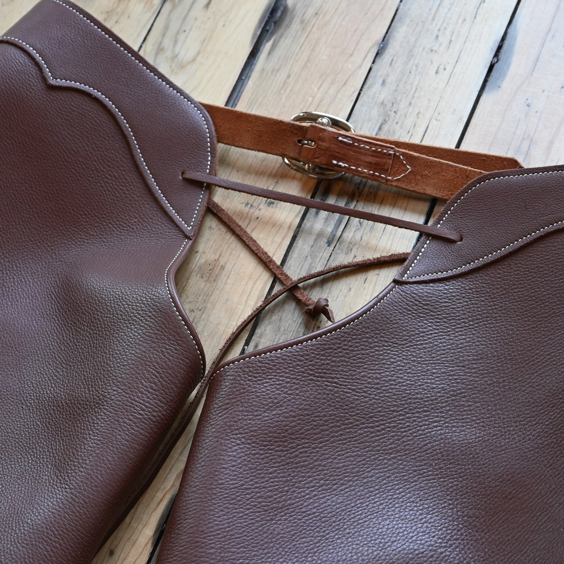 View of Weaver Shotgun Full Grain Chaps in brown oil-tanned leather with adjustable closures.