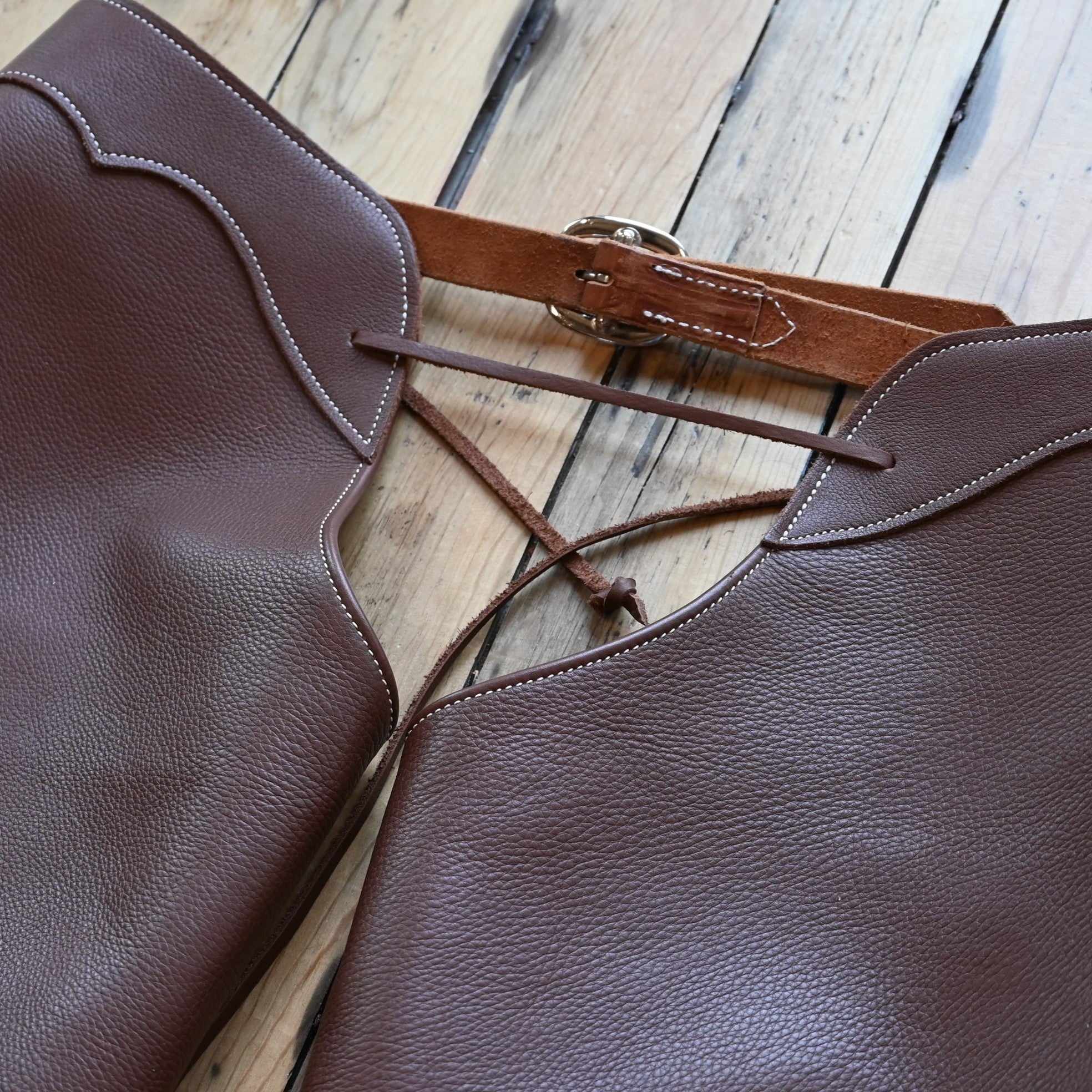 View of Weaver Shotgun Full Grain Chaps in brown oil-tanned leather with adjustable closures.