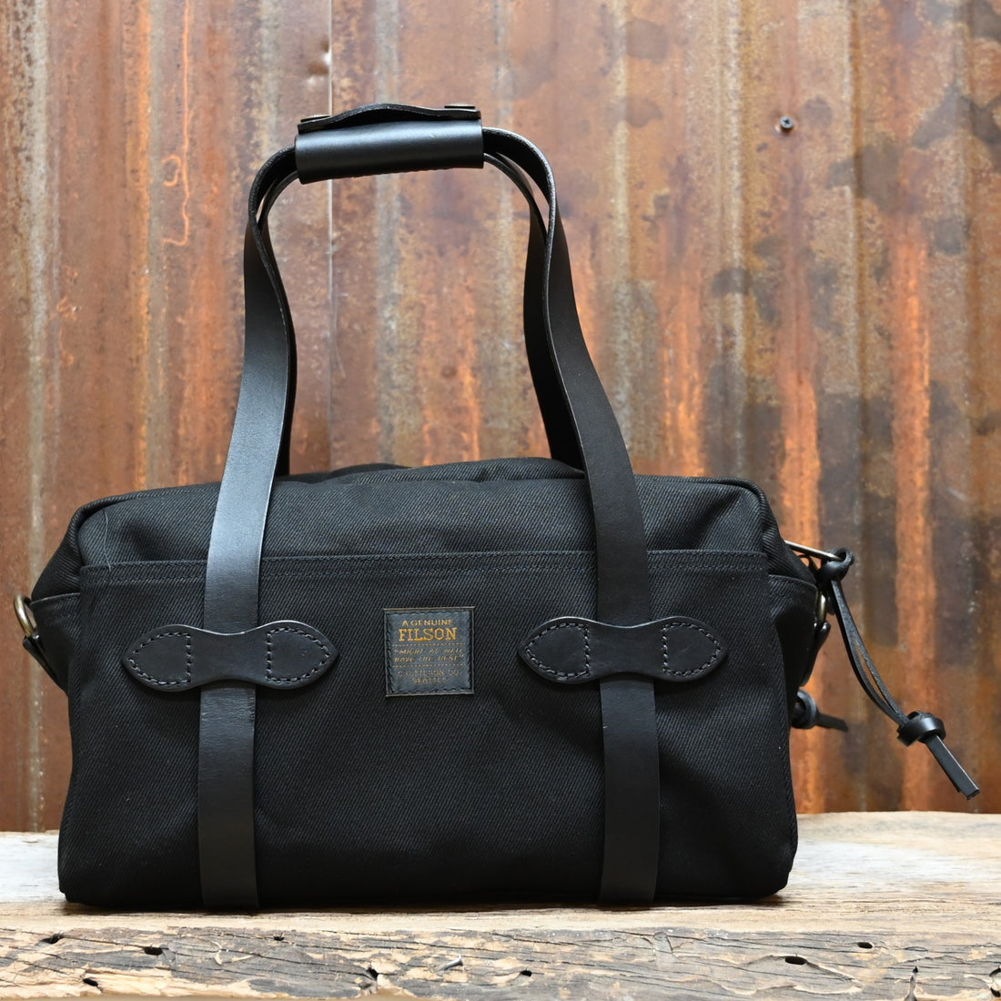 View of Filson Compact Duffle Bag in Black featuring vegetable-tanned Bridle Leather handles and a solid brass two-way zipper