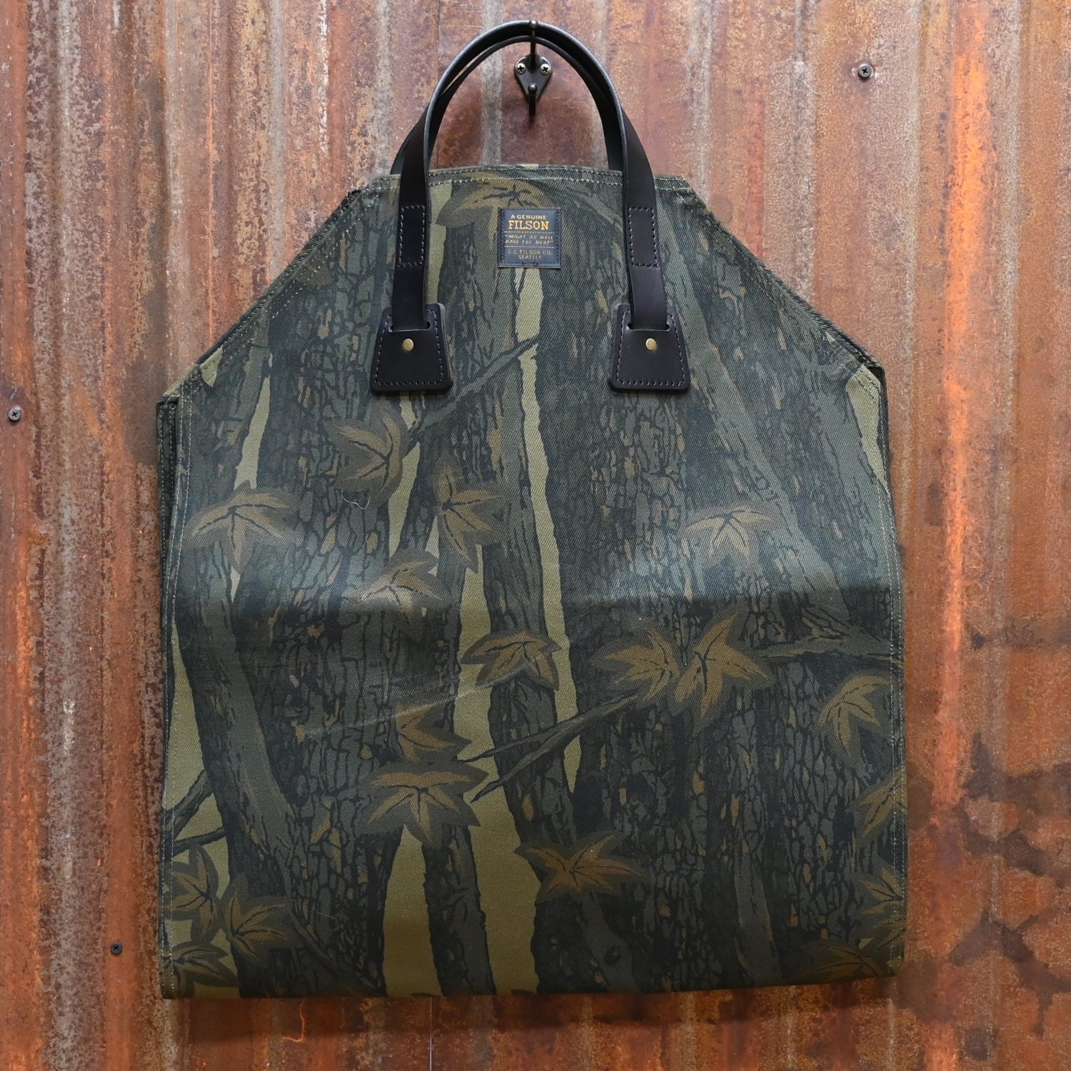 View of Filson Rugged Twill Log Carrier in Maple Bark Camo featuring Bridle Leather handles and water-resistant fabric