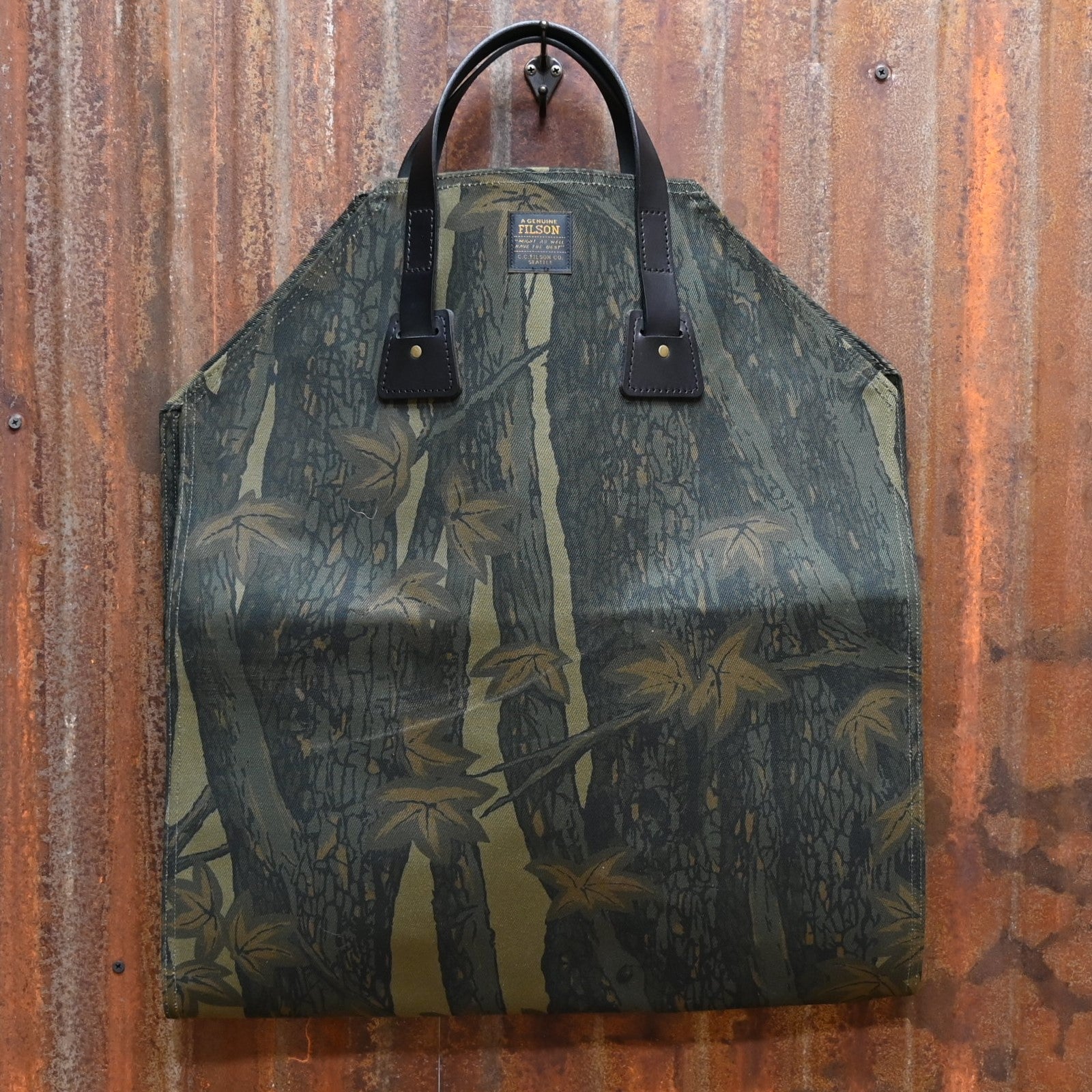 View of Filson Rugged Twill Log Carrier in Maple Bark Camo featuring Bridle Leather handles and water-resistant fabric