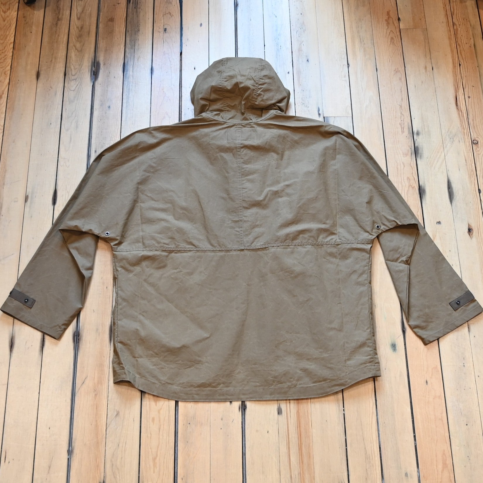 View of Filson Ranger Lightweight Anorak in Dark Beige, showcasing its waxed canvas fabric, adjustable hood, and snap-secure storm flap