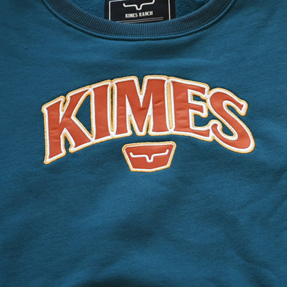 View of Kimes Ranch Ladies Colfax Crew Sweatshirt in Mid Blue, featuring an oversized fit, ribbed hem, and embroidered logo