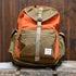 View of Filson Surveyor 36L Backpack in Dark Tan/Flame, featuring dry-waxed Cordura® nylon, padded laptop compartment, and multiple storage pockets