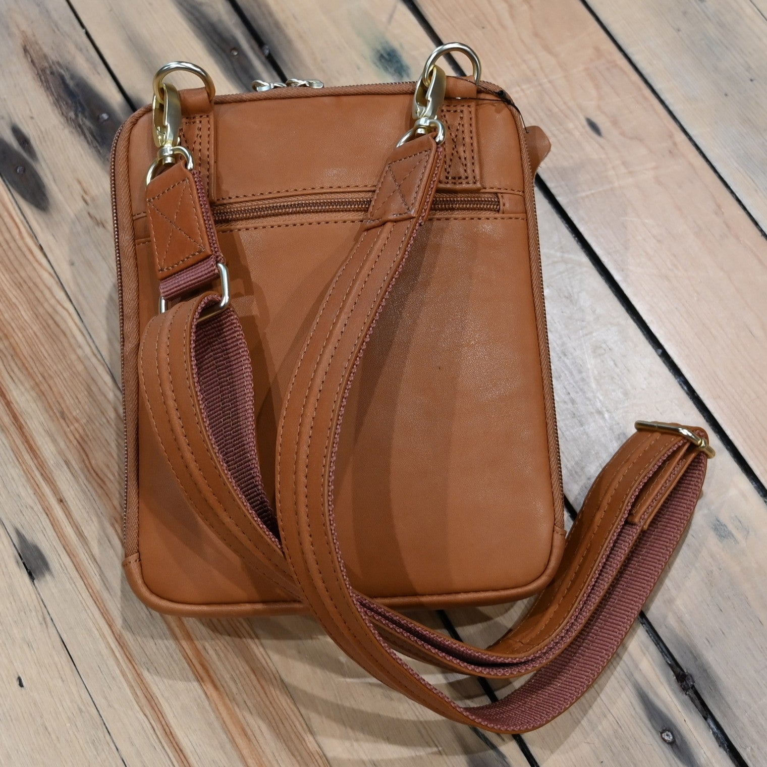 Tan leather crossbody shoulder pouch with embossed front, designed for concealed carry