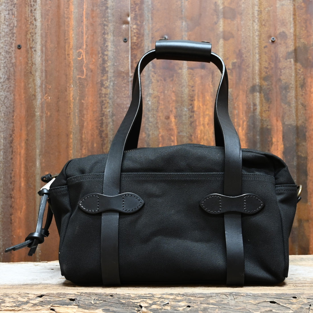 View of Filson Compact Duffle Bag in Black featuring vegetable-tanned Bridle Leather handles and a solid brass two-way zipper