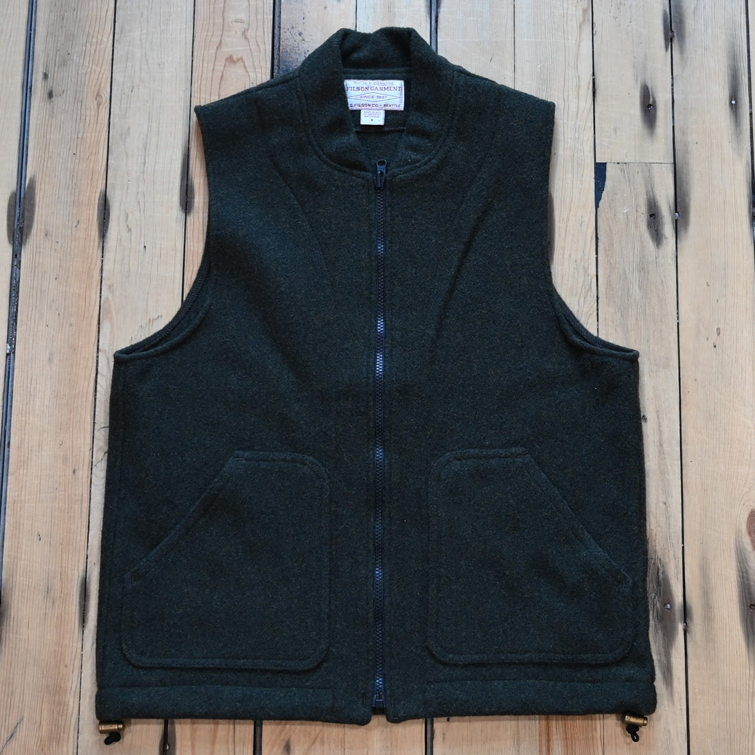 Forest green Filson Mackinaw Wool Vest Liner with zip-front, hand-warmer pockets, standing collar, and drawcord waist