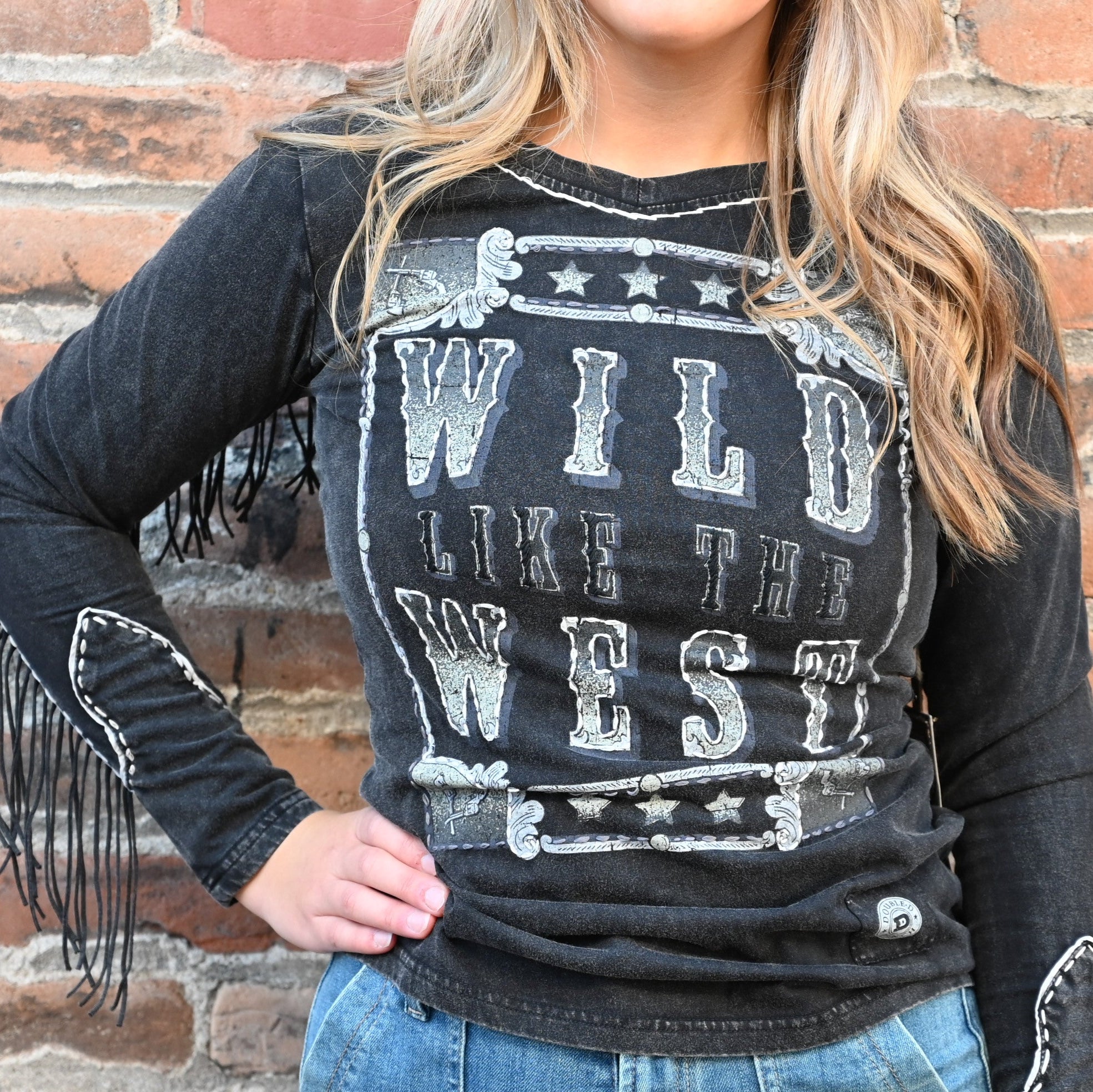 View of Double D Ranch Wild Like the West Tee featuring bold graphic and fringe detailing on long sleeves