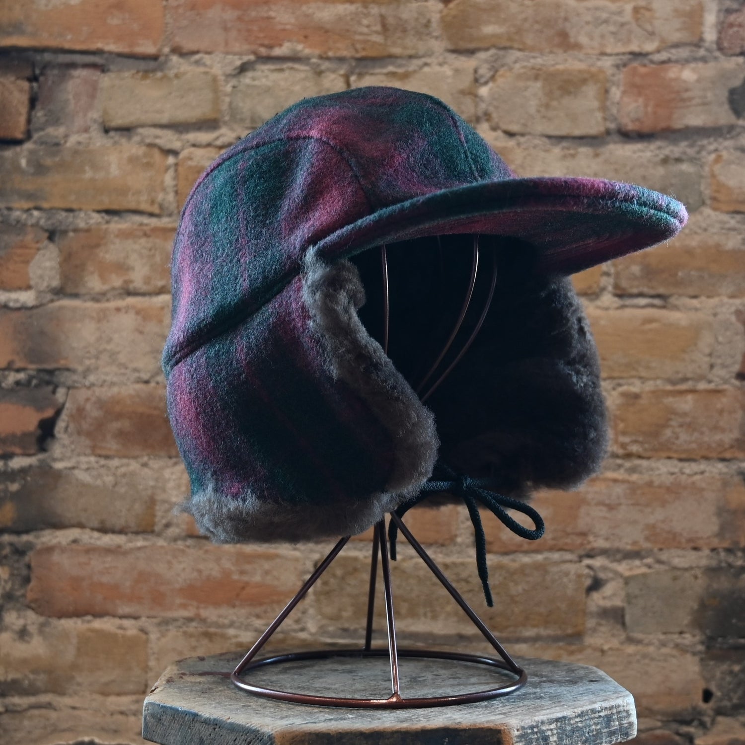 View of Filson Double Mackinaw Cap in Forest Green/Acorn and Burgundy/Dark Olive Plaid featuring shearling-lined earflaps and a 3&quot; bill