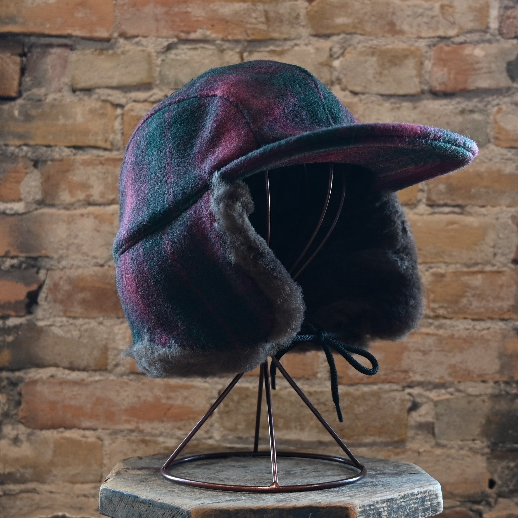 View of Filson Double Mackinaw Cap in Forest Green/Acorn and Burgundy/Dark Olive Plaid featuring shearling-lined earflaps and a 3&quot; bill