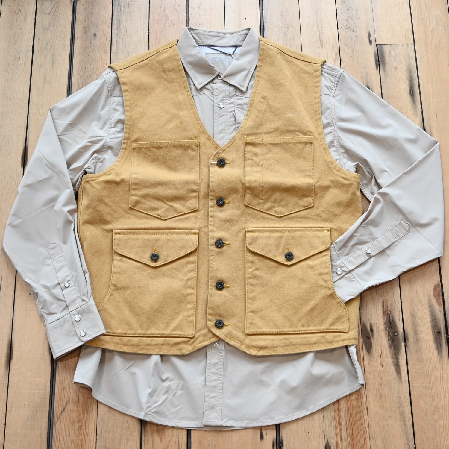 View of Schaefer brushcloth vest in suntan canvas with utility pockets and brass buttons