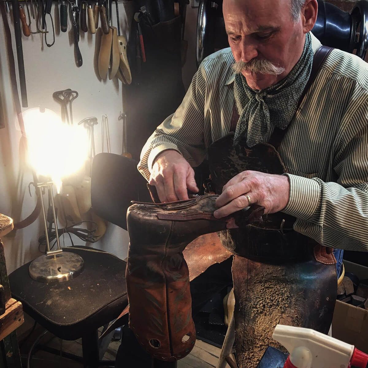 A photo of bootmaker Dan Schwarz repairing a leather boot in his workshop