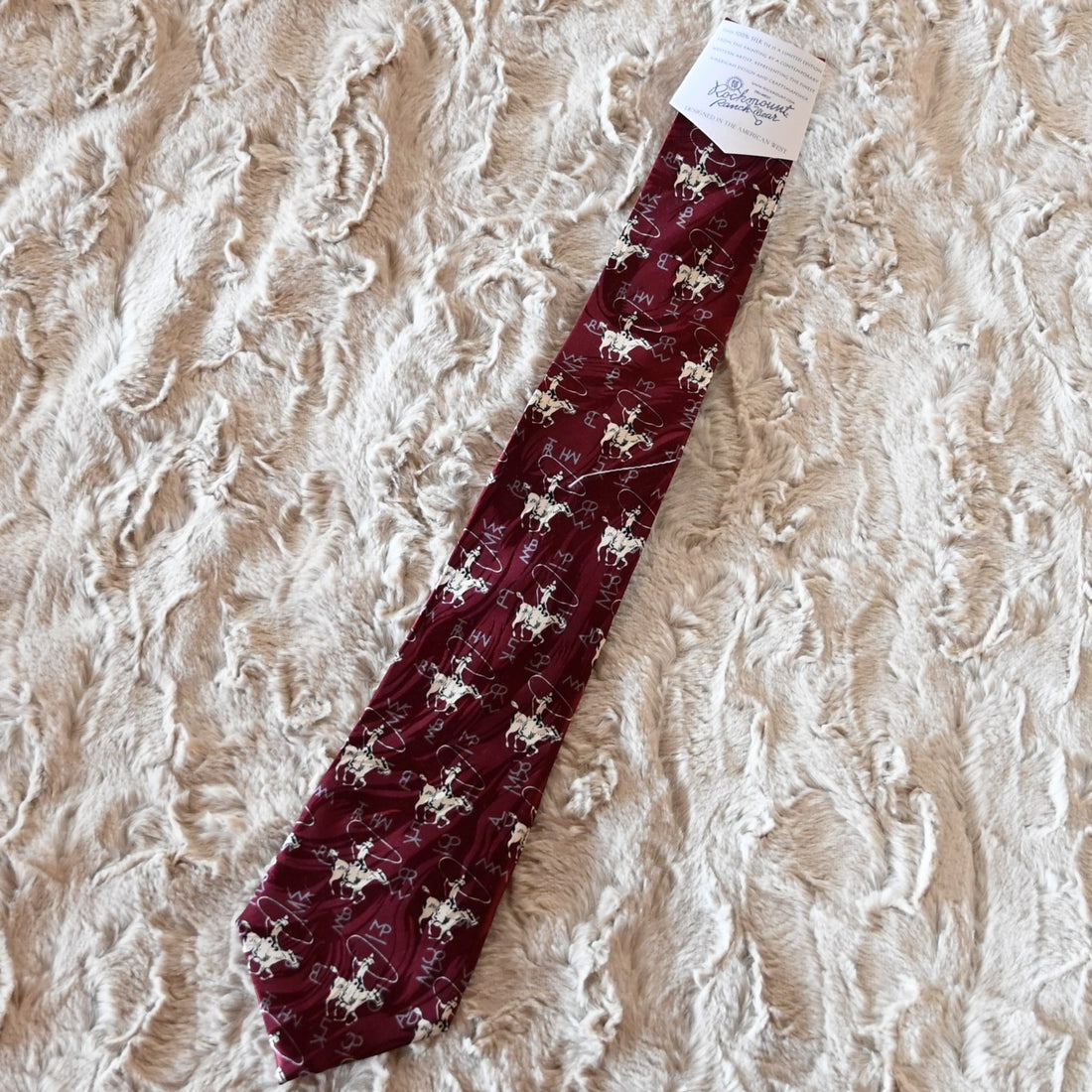 View of Rockmount burgundy silk necktie with roper figure and Tru‑West® branding