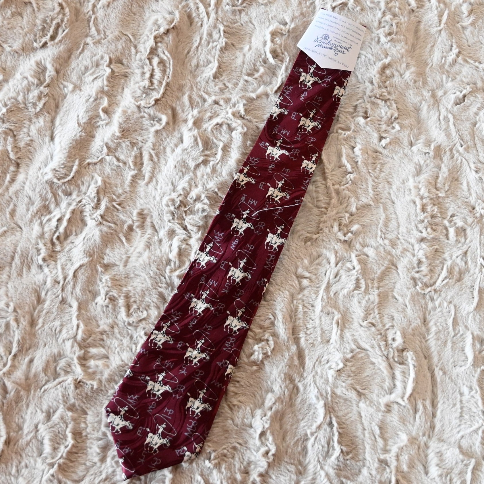 View of Rockmount burgundy silk necktie with roper figure and Tru‑West® branding