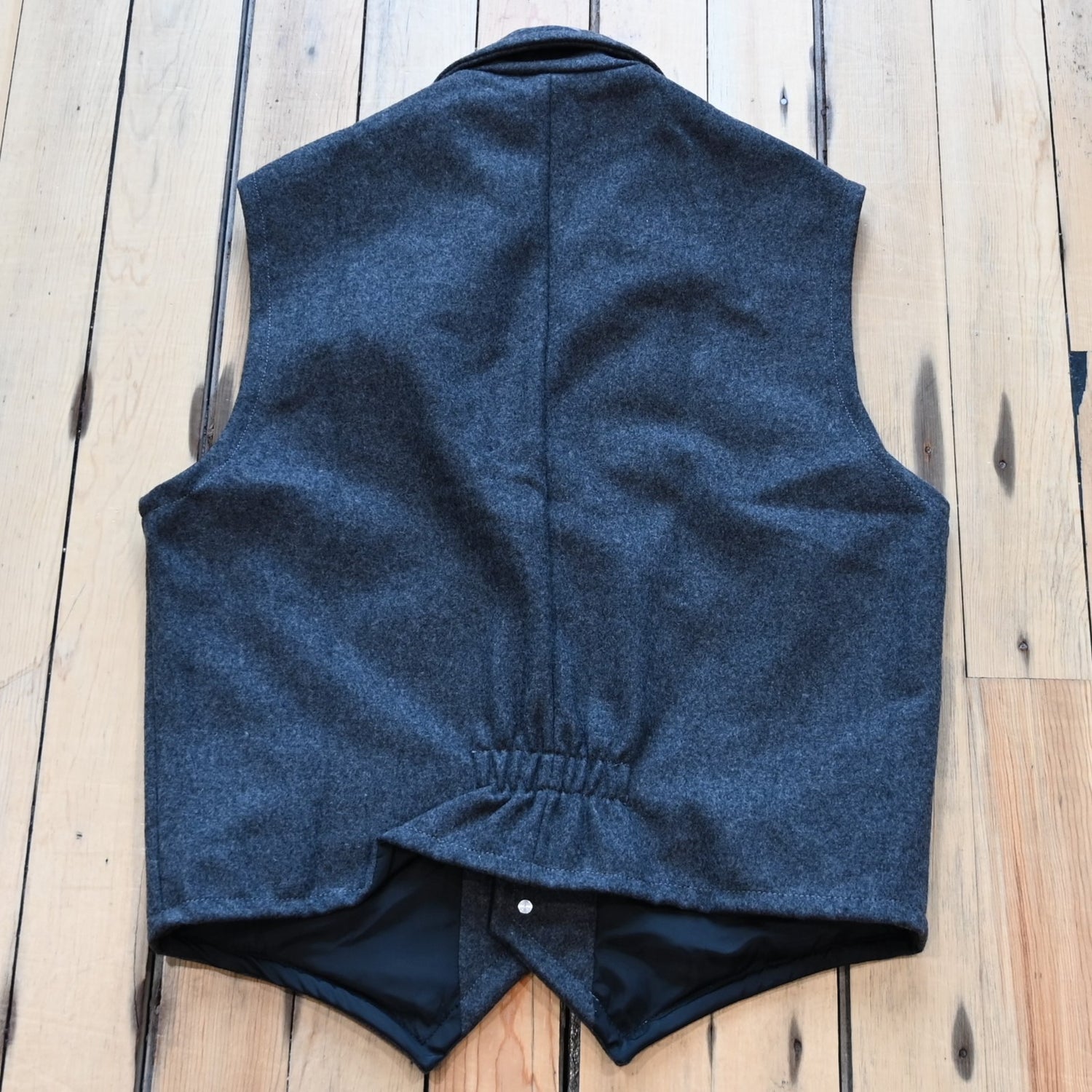 View of Charcoal Schaefer Cattle Baron wool vest with lapel collar, four pockets, and brass buttons