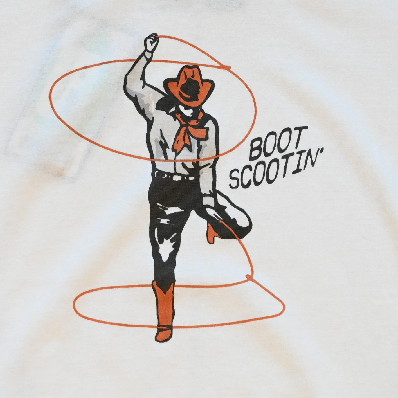 Ladies vintage white Boot Scootin’ boxy tee by Sendero with cowgirl roping graphic and cropped fit