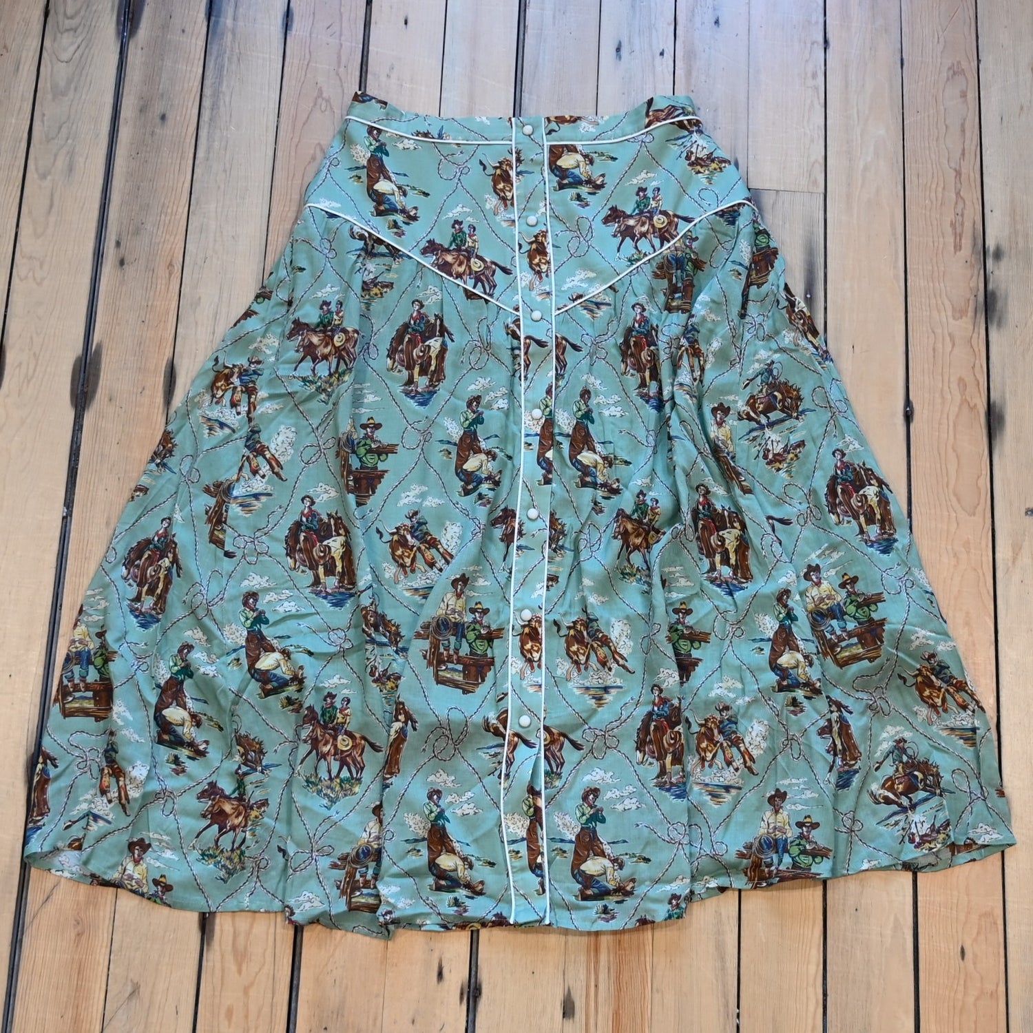 View of Double D Ranch Romance &amp; Rustlers Skirt featuring a custom Western print, contrast piping, and pearl snap placket in a midi A-line silhouette