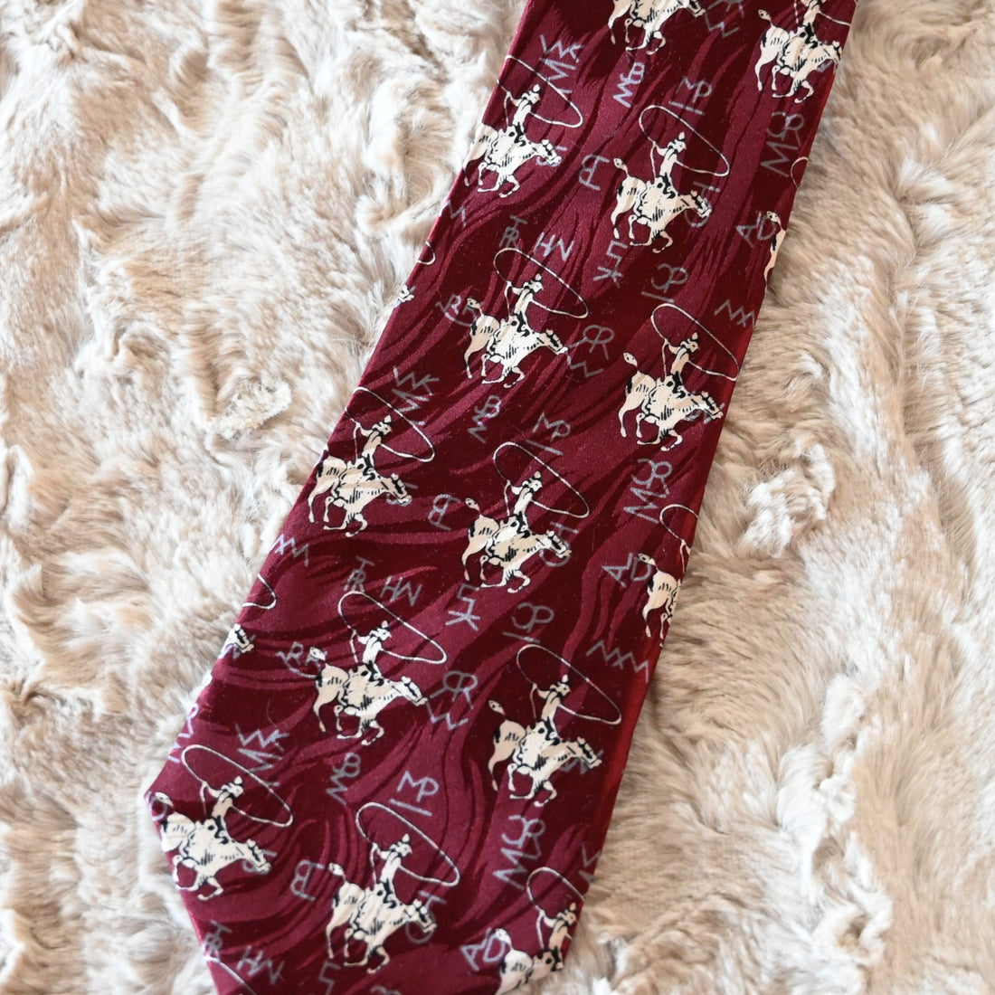 View of Rockmount burgundy silk necktie with roper figure and Tru‑West® branding