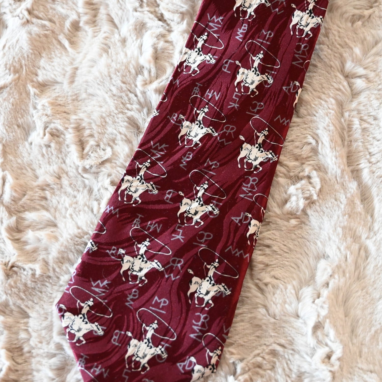 View of Rockmount burgundy silk necktie with roper figure and Tru‑West® branding