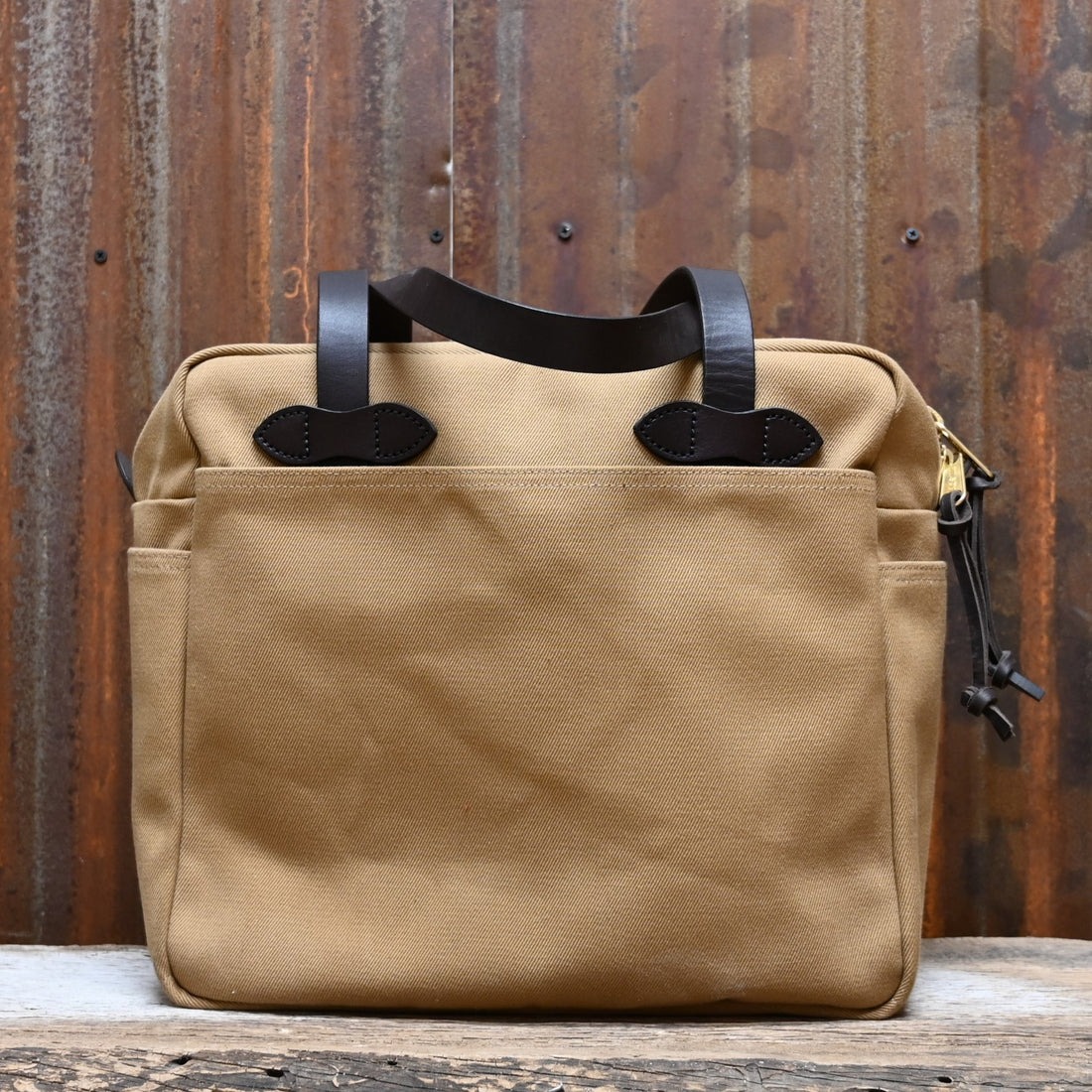 View of Filson Rugged Twill Tote Bag with Zipper in Tan, showcasing durable waxed cotton and leather handles