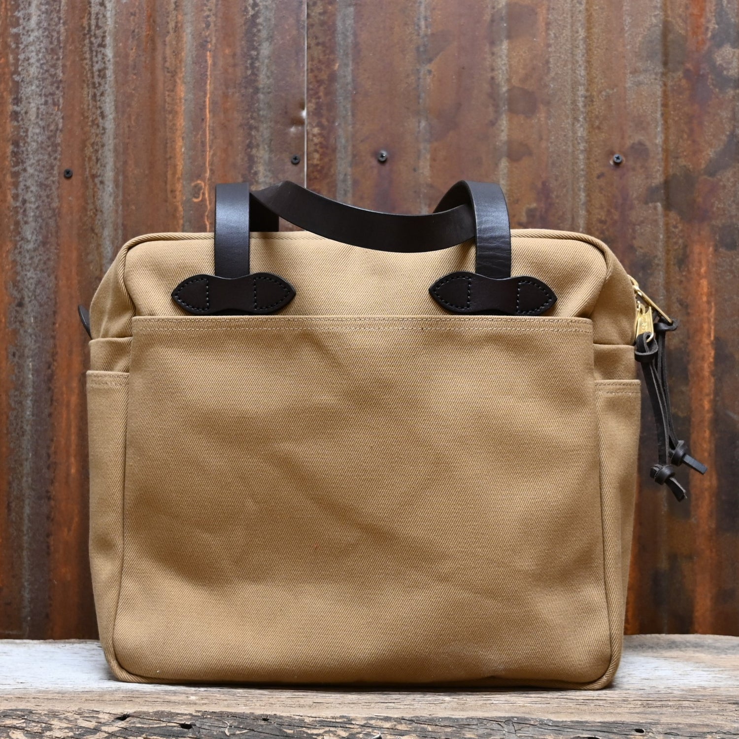 View of Filson Rugged Twill Tote Bag with Zipper in Tan, showcasing durable waxed cotton and leather handles