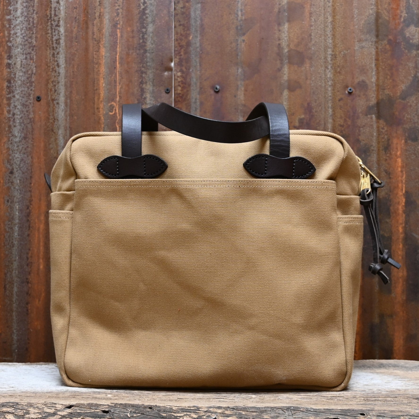 View of Filson Rugged Twill Tote Bag with Zipper in Tan, showcasing durable waxed cotton and leather handles